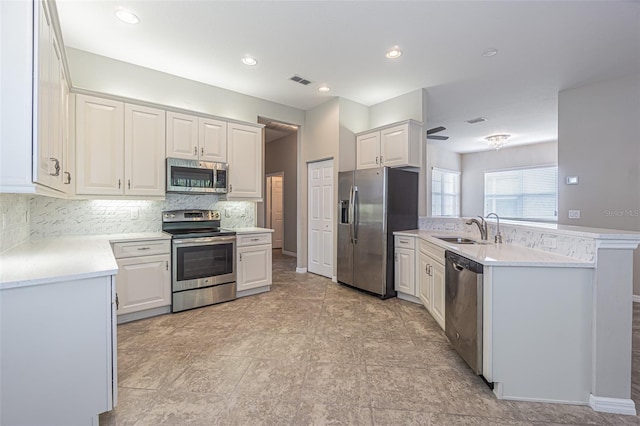 kitchen with backsplash, white cabinetry, sink, and appliances with stainless steel finishes