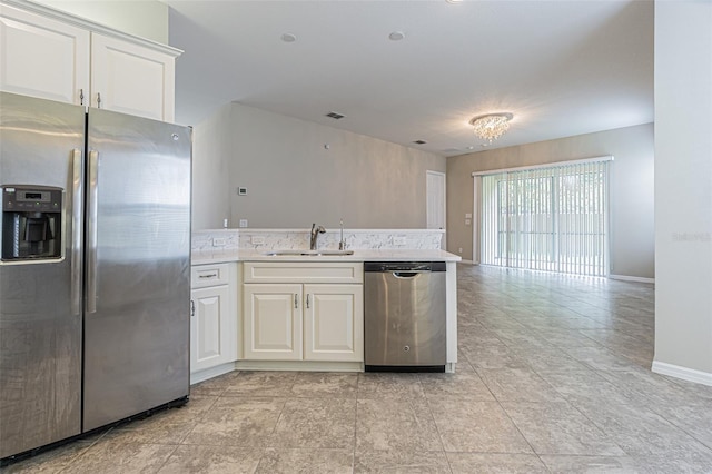 kitchen with sink, white cabinets, stainless steel appliances, and a notable chandelier