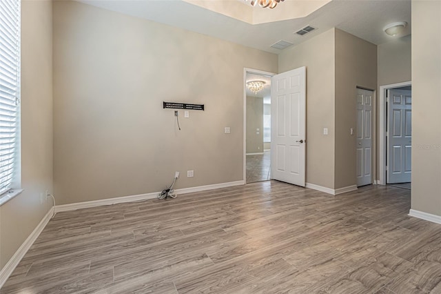 spare room featuring light hardwood / wood-style flooring and an inviting chandelier