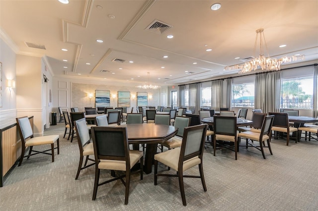 carpeted dining space featuring a chandelier and ornamental molding