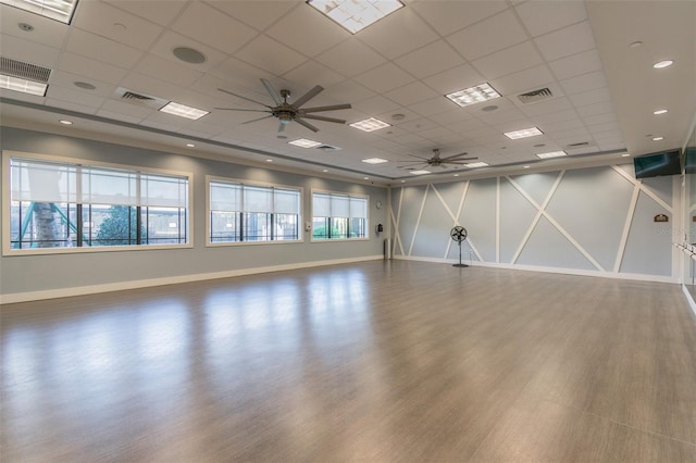 empty room with hardwood / wood-style floors, ceiling fan, and a drop ceiling