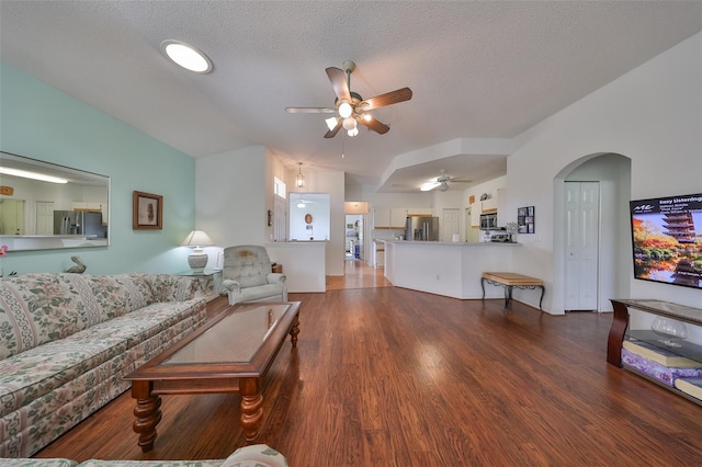 living room featuring ceiling fan, dark hardwood / wood-style flooring, and a textured ceiling