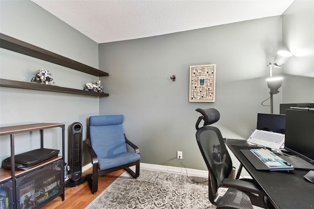 home office with light hardwood / wood-style floors and a textured ceiling