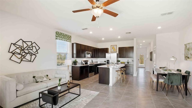 living room featuring ceiling fan, light tile patterned floors, and sink