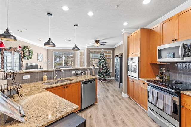 kitchen with sink, ceiling fan, appliances with stainless steel finishes, tasteful backsplash, and decorative light fixtures