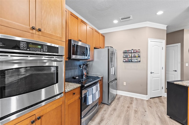 kitchen featuring light stone countertops, light hardwood / wood-style flooring, crown molding, a textured ceiling, and appliances with stainless steel finishes