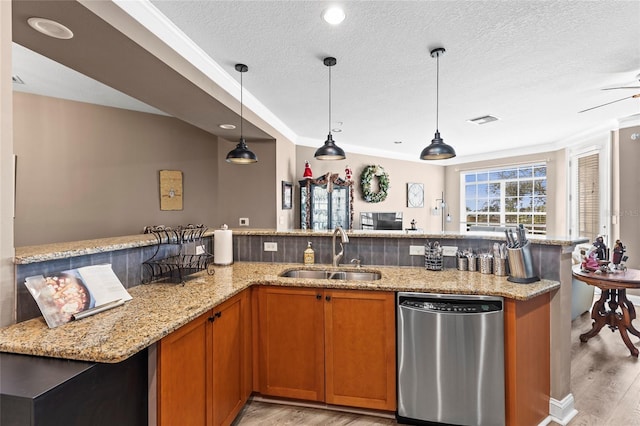 kitchen featuring sink, stainless steel dishwasher, light stone countertops, light wood-type flooring, and decorative light fixtures