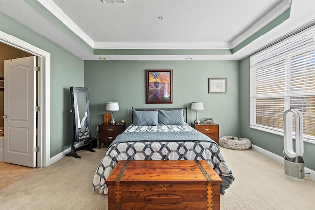 carpeted bedroom with a tray ceiling and crown molding