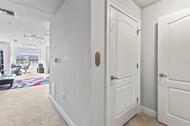 corridor with light carpet and a textured ceiling