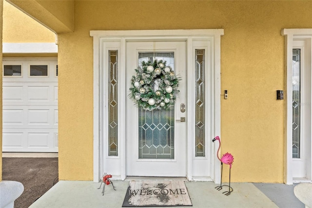 doorway to property featuring a garage and stucco siding