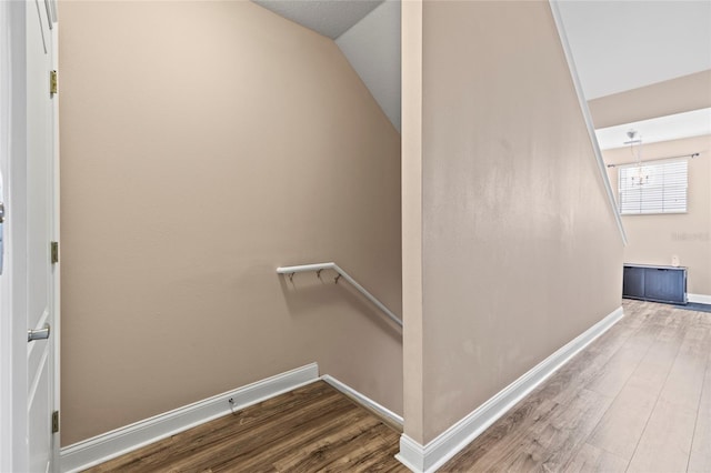 stairway featuring vaulted ceiling, baseboards, and wood finished floors