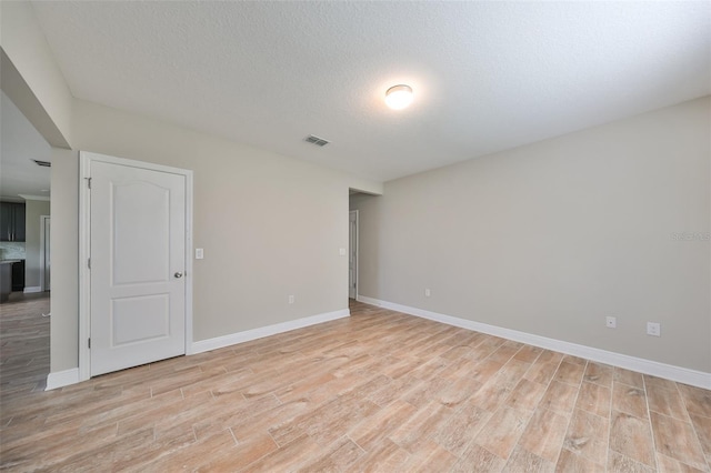 spare room featuring a textured ceiling and light hardwood / wood-style flooring