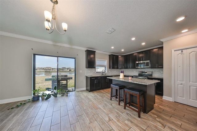 kitchen featuring a center island, stainless steel appliances, light stone counters, decorative light fixtures, and a breakfast bar