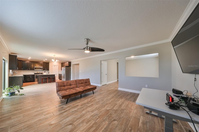 living room featuring ceiling fan with notable chandelier, light hardwood / wood-style floors, and crown molding