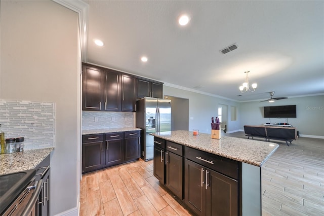 kitchen with a center island, stainless steel fridge with ice dispenser, backsplash, crown molding, and ceiling fan with notable chandelier