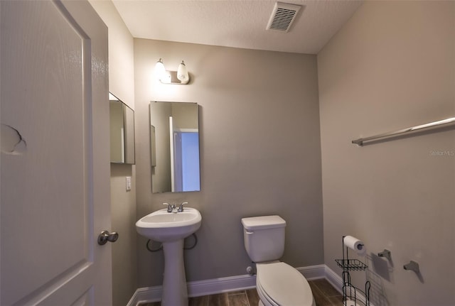 bathroom featuring sink, wood-type flooring, a textured ceiling, and toilet