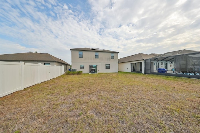 back of property with a lawn and a lanai