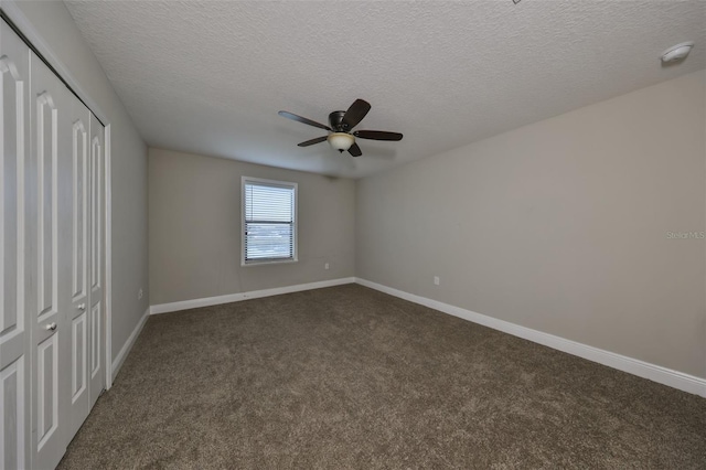 unfurnished bedroom featuring ceiling fan, dark carpet, a textured ceiling, and a closet