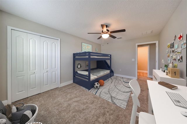 carpeted bedroom featuring a textured ceiling, a closet, and ceiling fan