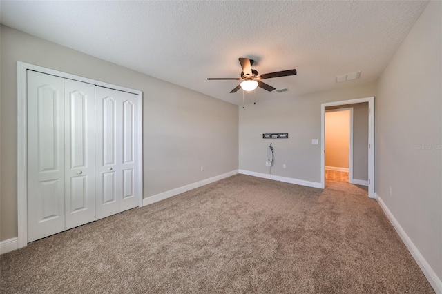 unfurnished bedroom with carpet flooring, ceiling fan, a closet, and a textured ceiling