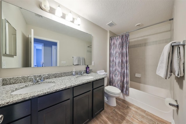 full bathroom featuring shower / bath combo with shower curtain, vanity, a textured ceiling, and toilet