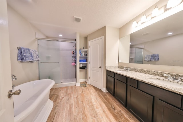 bathroom featuring a textured ceiling, vanity, and shower with separate bathtub