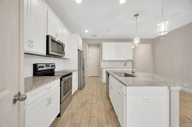 kitchen with sink, an island with sink, white cabinets, and appliances with stainless steel finishes