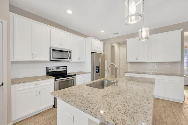 kitchen featuring hanging light fixtures, white cabinetry, appliances with stainless steel finishes, and sink