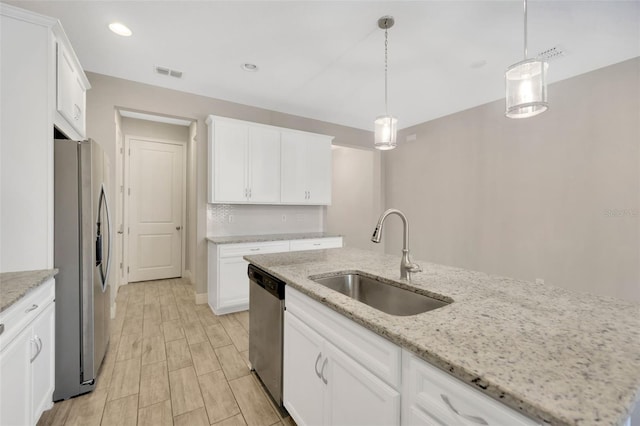 kitchen with sink, white cabinetry, a center island with sink, pendant lighting, and stainless steel appliances