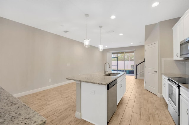 kitchen featuring sink, an island with sink, pendant lighting, stainless steel appliances, and white cabinets