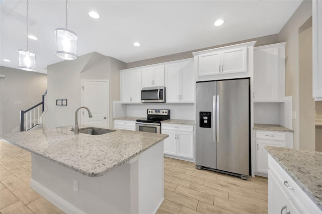 kitchen featuring sink, white cabinetry, hanging light fixtures, stainless steel appliances, and an island with sink