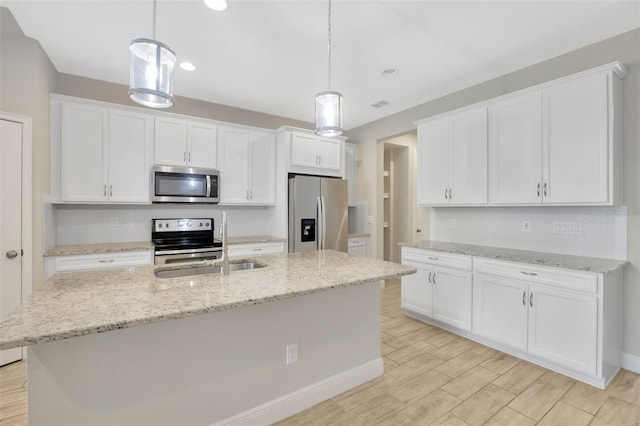 kitchen with pendant lighting, white cabinetry, stainless steel appliances, and a center island with sink