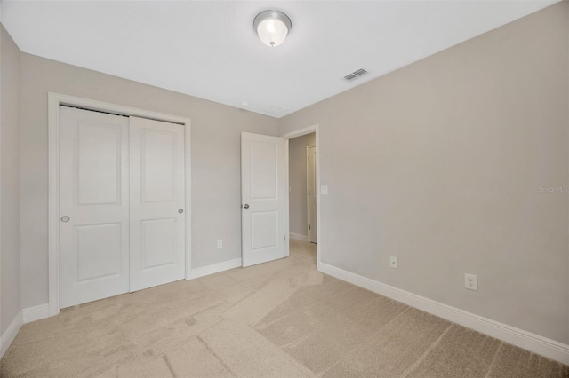 unfurnished bedroom featuring light colored carpet and a closet