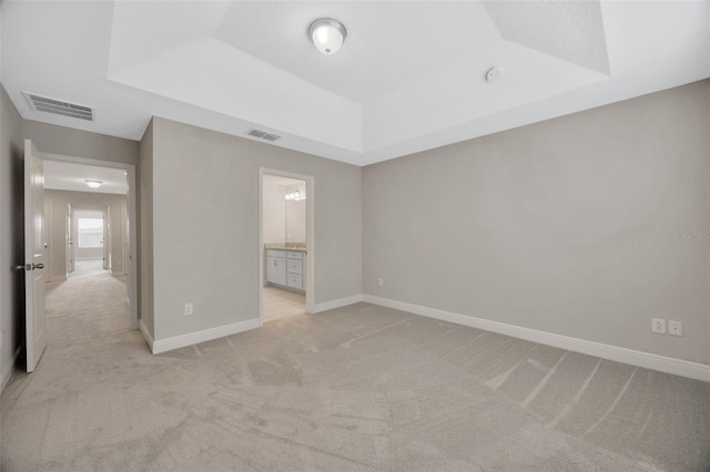 unfurnished room with a tray ceiling and light carpet