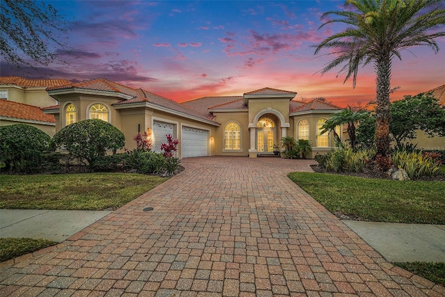 mediterranean / spanish-style home featuring a garage and a yard