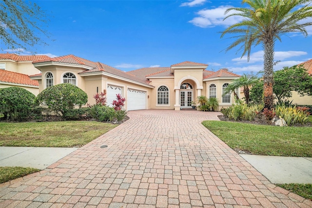 mediterranean / spanish home with a garage, a front lawn, and french doors