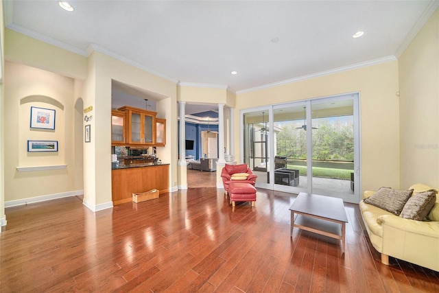 living room featuring decorative columns, crown molding, and dark hardwood / wood-style flooring