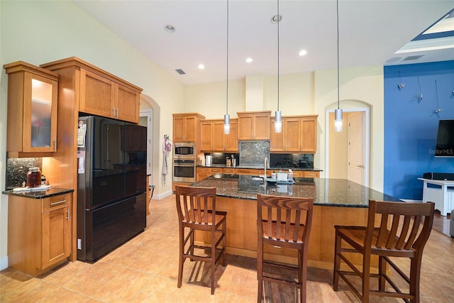 kitchen with a kitchen breakfast bar, pendant lighting, a center island with sink, decorative backsplash, and stainless steel appliances