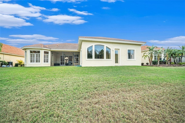 back of property with a lawn and a sunroom