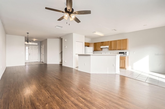 unfurnished living room featuring ceiling fan with notable chandelier and light wood-type flooring