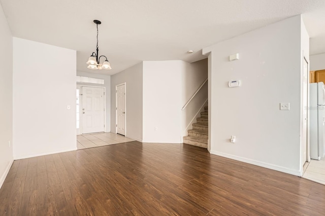 unfurnished living room with hardwood / wood-style flooring and an inviting chandelier