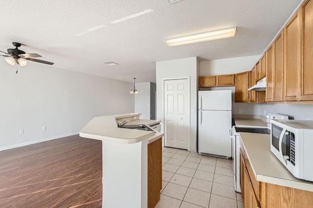 kitchen with ceiling fan, sink, an island with sink, decorative light fixtures, and white appliances