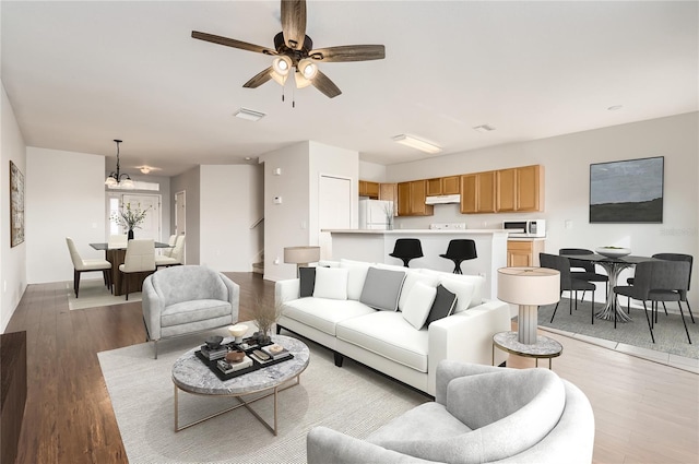 living room with ceiling fan with notable chandelier and light wood-type flooring