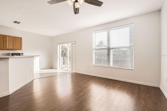 unfurnished living room with ceiling fan and dark wood-type flooring