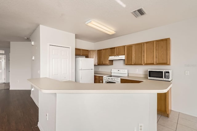 kitchen with a textured ceiling, light tile patterned floors, a spacious island, and white appliances