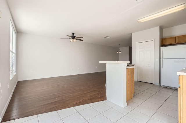 kitchen with ceiling fan with notable chandelier, white fridge, light tile patterned floors, and hanging light fixtures