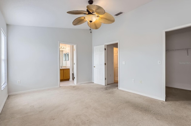 unfurnished bedroom with ceiling fan, a spacious closet, connected bathroom, light colored carpet, and a closet