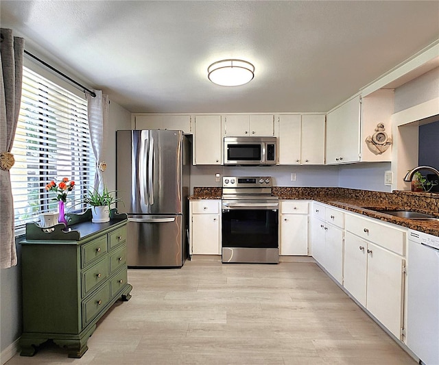 kitchen featuring white cabinetry, sink, stainless steel appliances, and light wood-type flooring