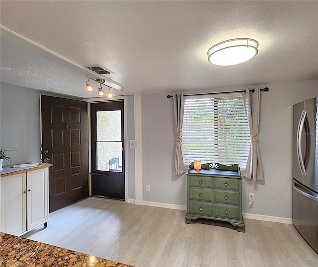 entryway with light hardwood / wood-style floors and a textured ceiling