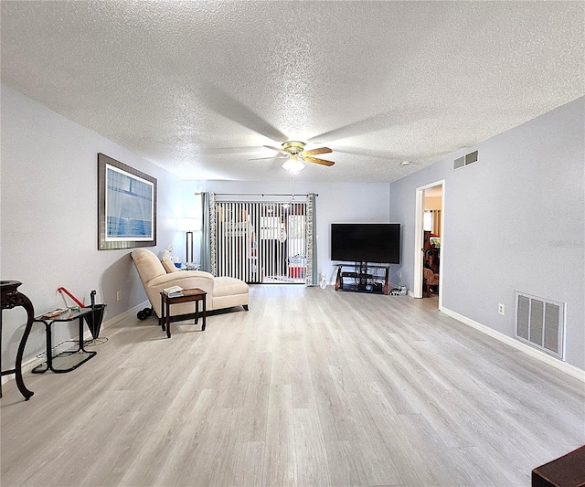 living room featuring a textured ceiling, light hardwood / wood-style floors, and ceiling fan